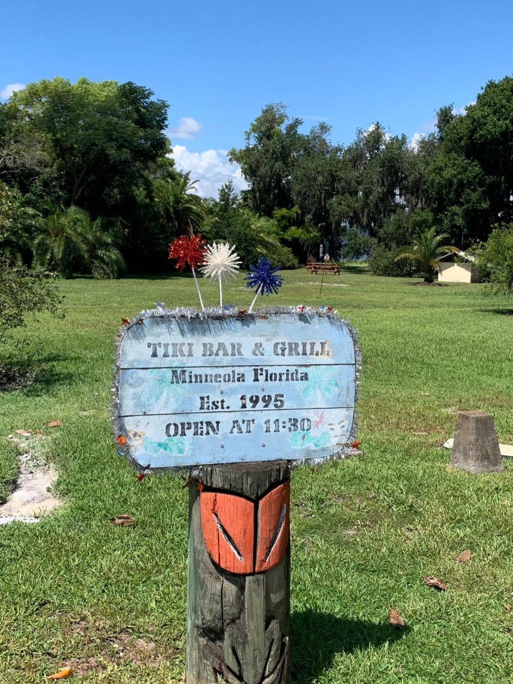 The hand-painted Tiki Bar & Grill sign at the entrance in Minneola, Florida — established 1995